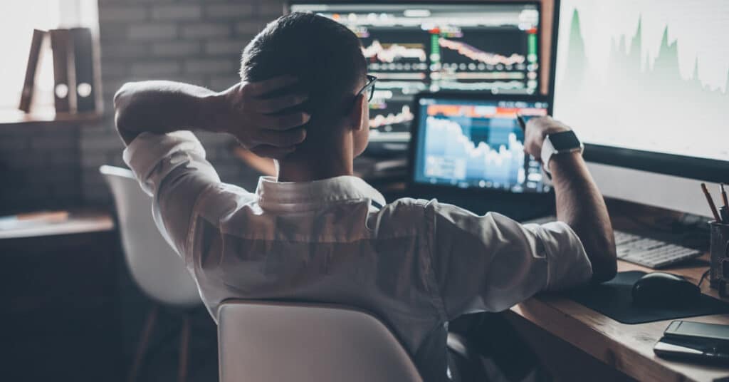 Man sitting in front of several computer screens looking at B2B marketing data.