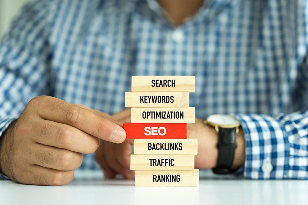 Man stacking wooden blocks with words on them to illustrate the concept of an SEO audit.